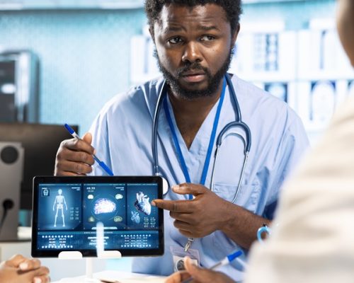 Group of healthcare specialists in scrubs analyzing results with doctor, emphasizing teamwork, professional training and care management in a modern office. Medical staff doing research.